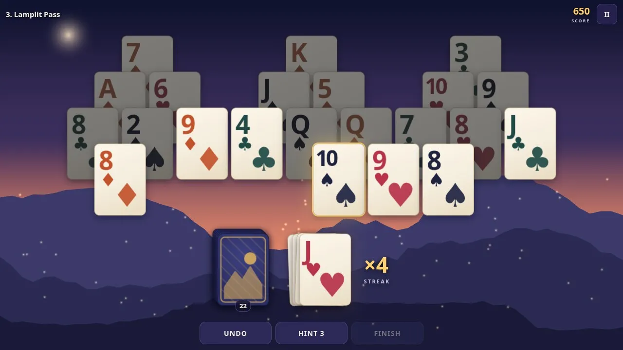 Gloamridge in play: cards on three peaks at dusk over a mountain range, a streak of 4 on the waste pile